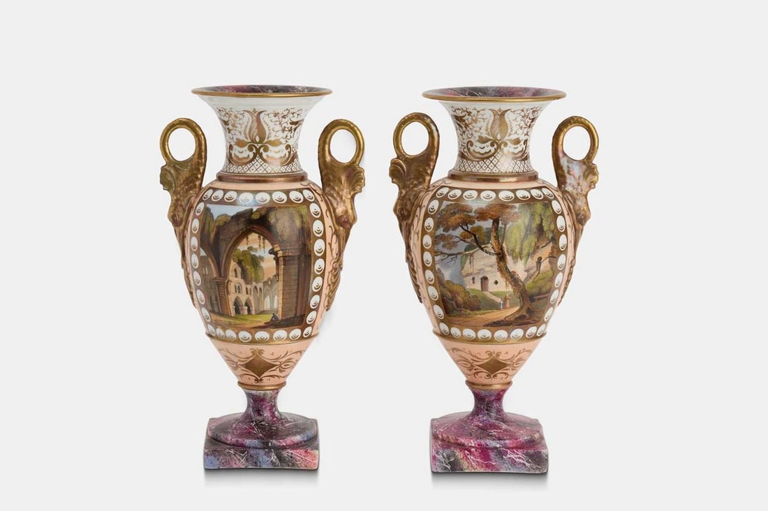A pair of Paris porcelain topographical urn vases, 19th century, French,: A pair of Paris porcelain topographical urn vases, 19th century, French, twin-handled, each with gilt highlights and an enamelled reserve, raised on a faux marble socle base (13cm wide, 10cm deep, 23c