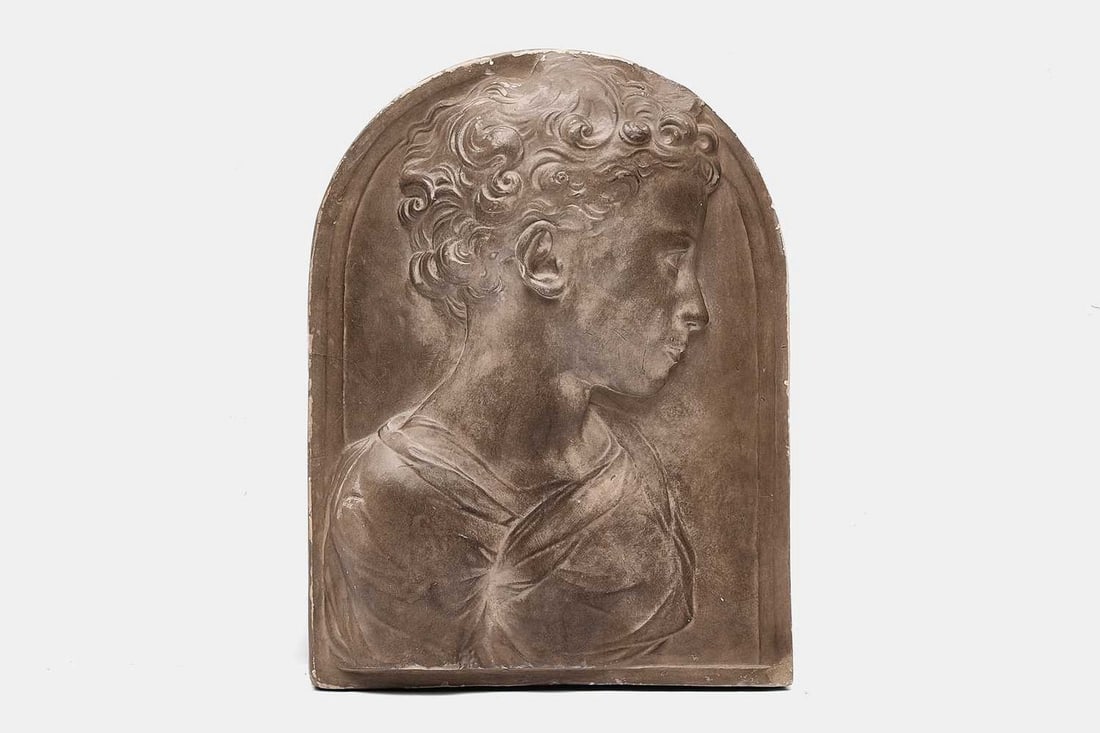A plaster relief panel of a child, 20th century, by l'Atelier de moulage du Louvre factory,: A plaster relief panel of a child, 20th century, by l'Atelier de moulage du Louvre factory, possibly depicting St John the Baptist as an infant, carved in relief, with maker's cartouche verso (30.5cm 