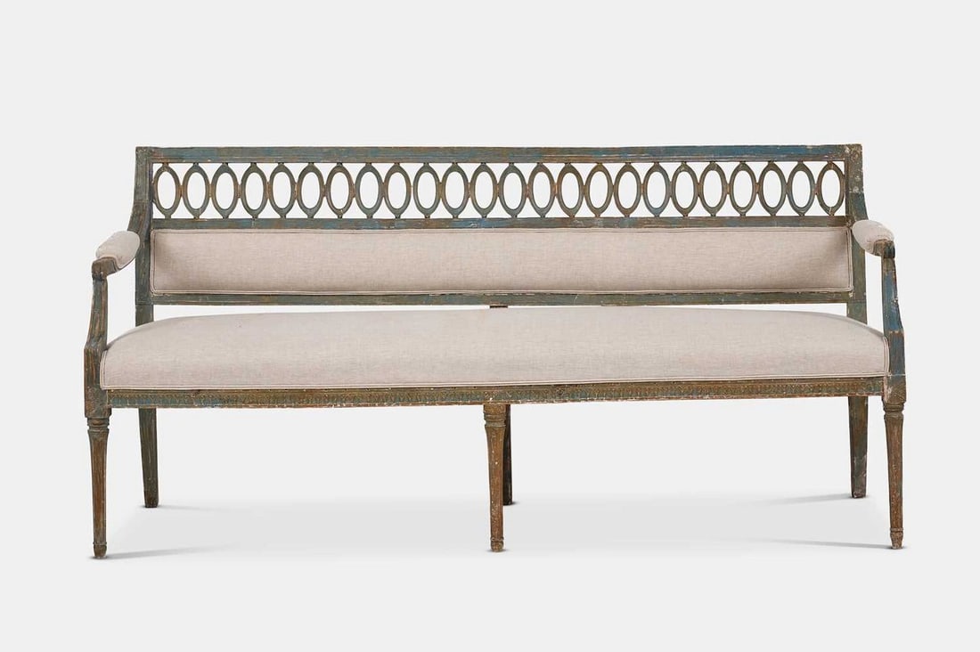 A Gustavian painted wooden settee, early 19th century, Northern European,: A Gustavian painted wooden settee, early 19th century, Northern European, with a pierced top rail above a padded back, open arms and seat, raised on tapering fluted supports (177cm wide, 67cm deep, 85