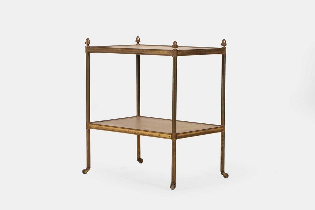 A Regency-style brass and leather étagère, late 19th century,: A Regency-style brass and leather étagère, late 19th century, composed of two tiers, each fitted with an inset gilt-tooled leather surface, raised on castors (47cm wide, 32cm deep, 55cm high) Proven
