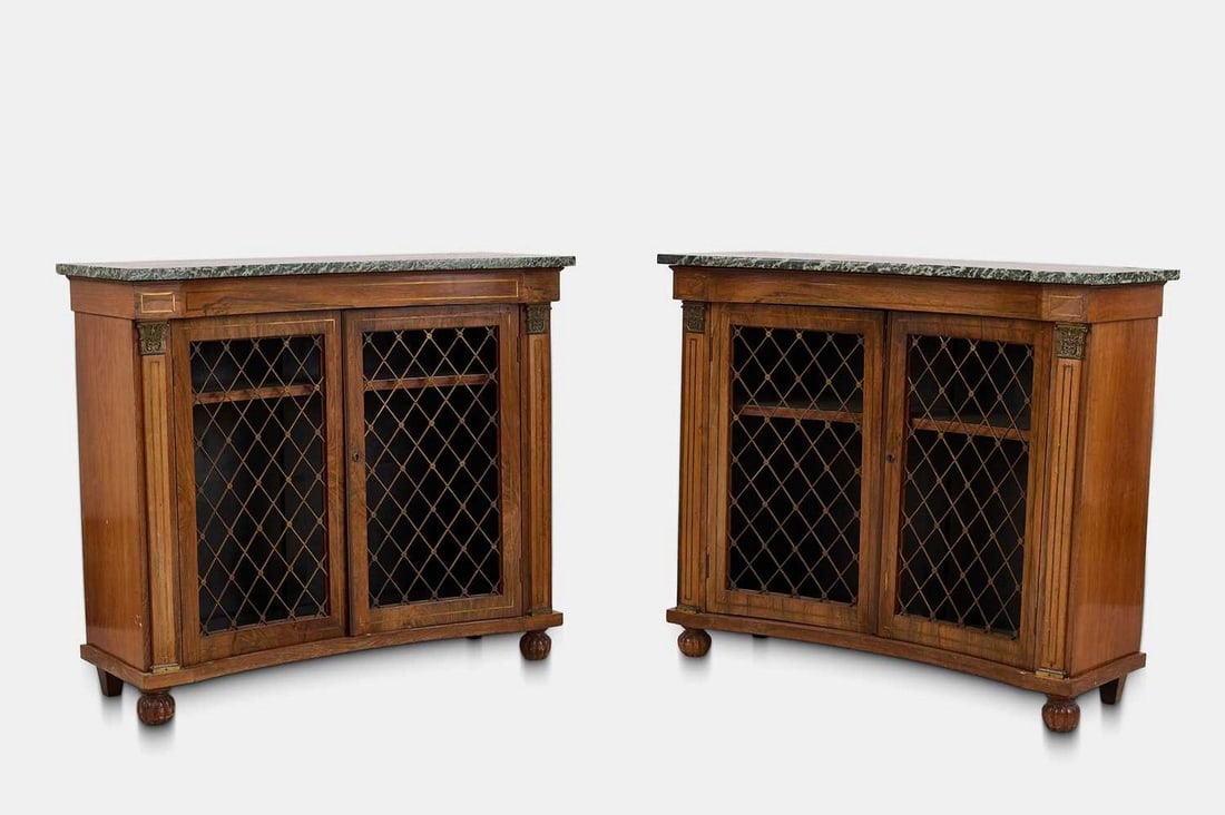 A pair of Regency-style rosewood low bookcases, early 20th century,: A pair of Regency-style rosewood low bookcases, early 20th century, each of concave outline, with a green marble top above a pair of brass grille doors, raised on lobed bun feet (100.5cm wide, 39cm de