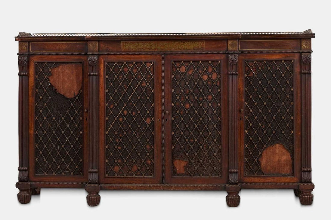 A George IV rosewood and brass side cabinet attributed to Gillows, circa 1830,: A George IV rosewood and brass side cabinet attributed to Gillows, circa 1830, of breakfront outline, with grille doors and cut-brass detail, raised on gadrooned bun feet (167cm wide, 44cm deep, 98cm 