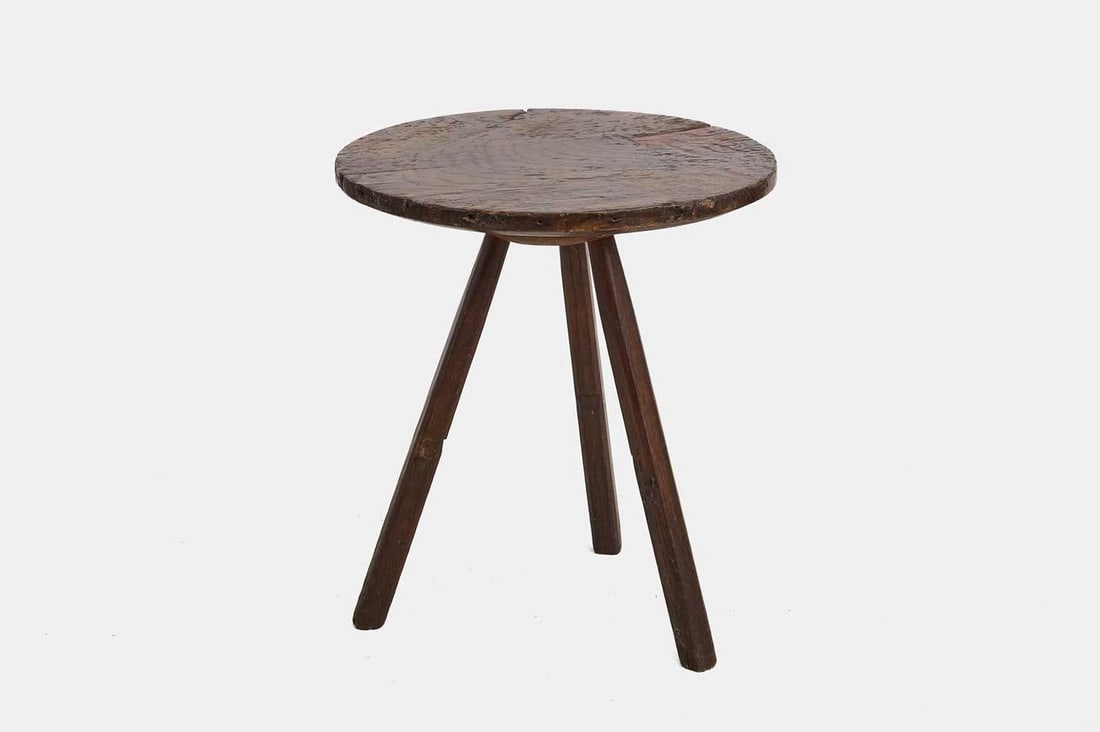 A primitive elm cheese-top cricket table, 19th century,: A primitive elm cheese-top cricket table, 19th century, with a thick circular top raised on splayed legs (63cm diameter, 73cm high) Condition Report: General knocks, wear and abrasions commensurate wi