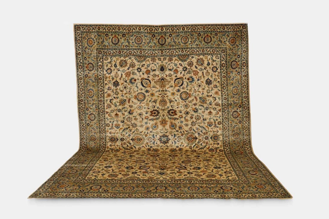 A Kashan wool carpet, circa 1930, Persian,: A Kashan wool carpet, circa 1930, Persian, woven with palmettes and stylised foliate motifs to a pale ground (426 x 327cm) Condition Report: Please note: although we try to reproduce colours as closel