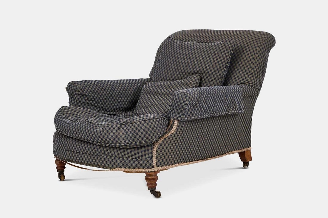 A late Victorian walnut club armchair by Howard & Sons, circa 1890,: A late Victorian walnut club armchair by Howard & Sons, circa 1890, upholstered in blue chequered fabric by Nina Campbell, raised on ring-turned front supports terminating in brass castors, the rear l