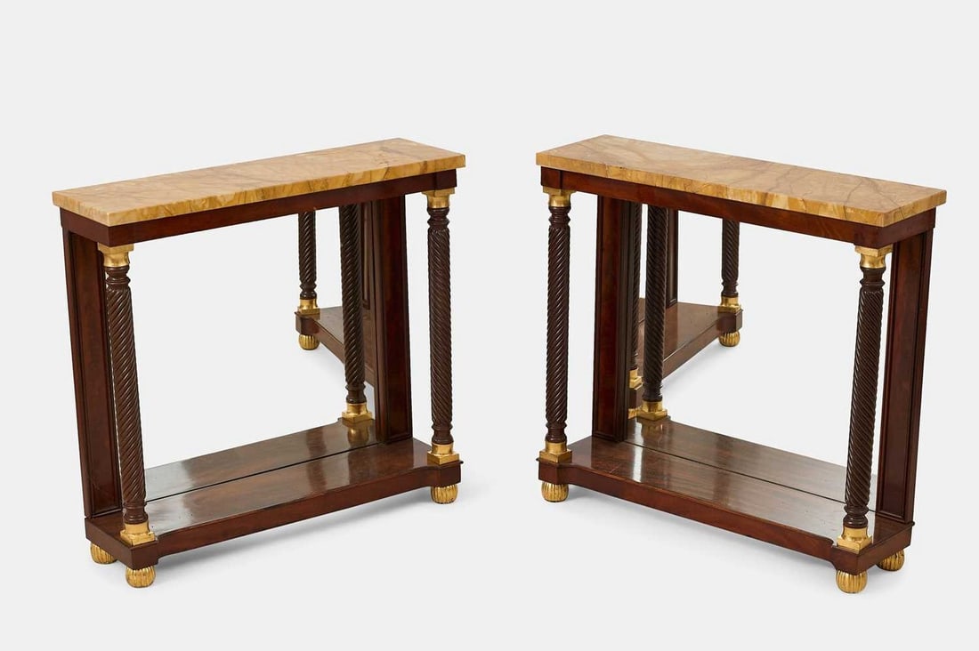 A pair of Regency-style mahogany and parcel-gilt pier tables, 20th century,: A pair of Regency-style mahogany and parcel-gilt pier tables, 20th century, each with a Siena marble top over a mirror back, flanked by spiral-twist supports and raised on reeded ball feet (92cm wide,