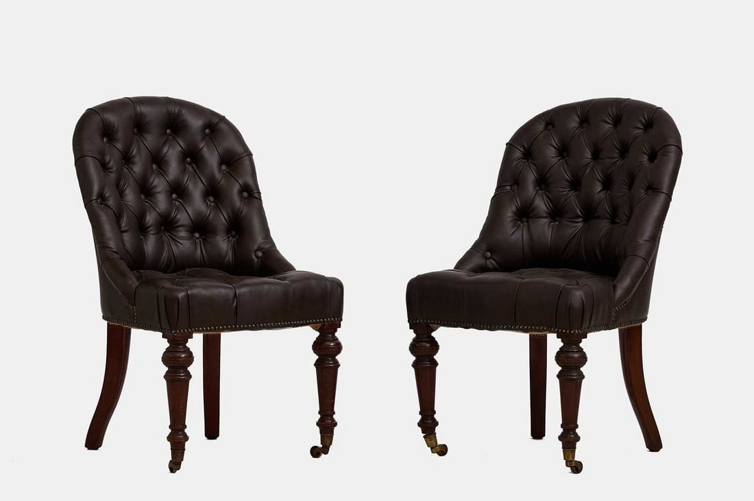 A pair of mahogany and leather library chairs by Howard & Sons, circa 1880,: A pair of mahogany and leather library chairs by Howard & Sons, circa 1880, each covered in buttoned brown leather upholstery, the rounded back over a stuffover seat, raised on ring-turned tapering fr