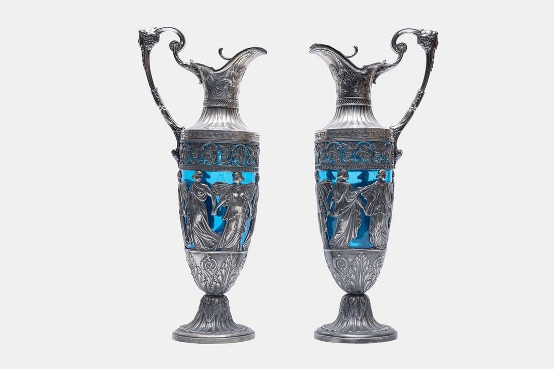 A pair of WMF silver-plated ewers, circa 1900, German, retailed by Henri Hypollite Decugis of: A pair of WMF silver-plated ewers, circa 1900, German, retailed by Henri Hypollite Decugis of Constantinople, each with a blue glass liner, decorated throughout with neoclassical motifs, the base mark