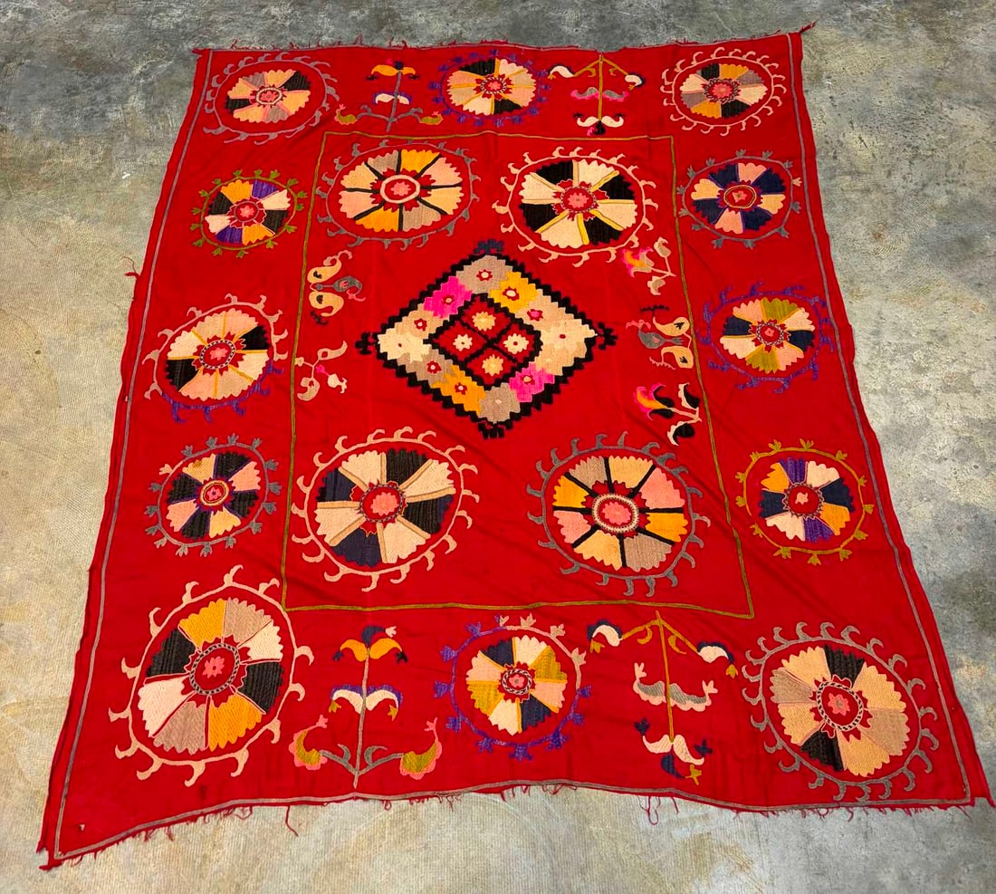 A large Suzani textile covering, late 19th century,: A large Suzani textile covering, late 19th century, on red ground with embroidered motifs, 85 x 195cm Condition Report: Frayed short ends and with some holes.