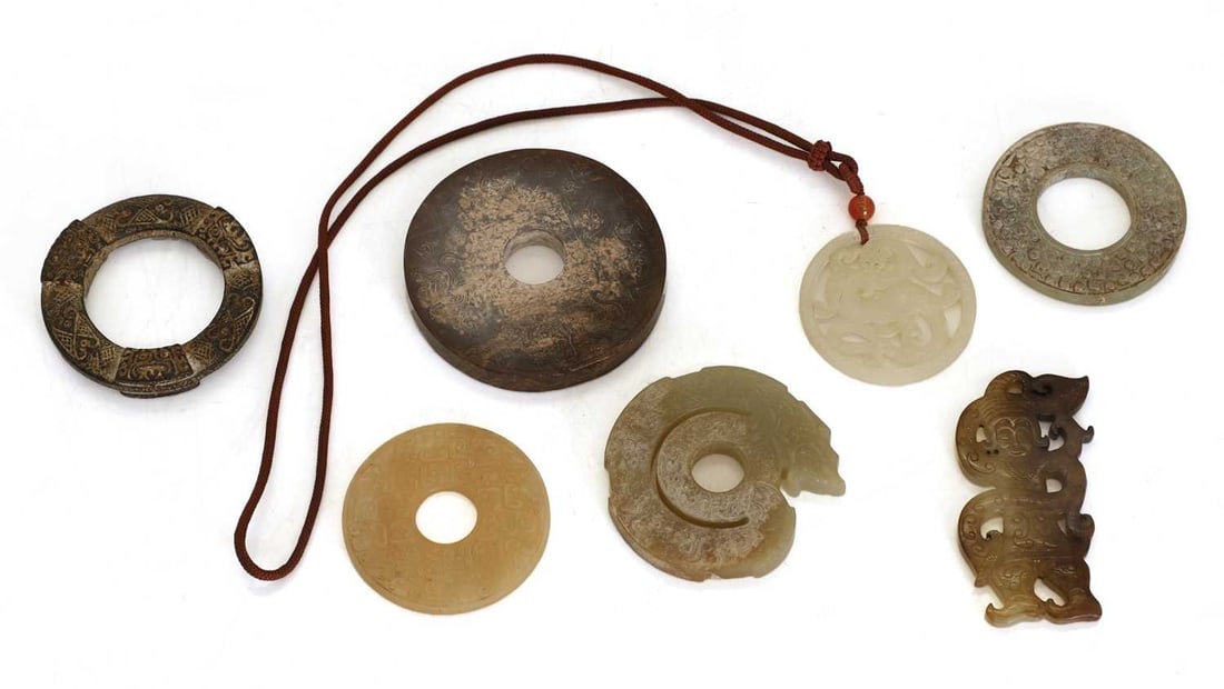 A collection of Chinese jade and hardstone,: A collection of Chinese jade and hardstone, comprising: two bi disks, each carved with archaic scrolls, two circular pendants, a pendant in the form of a coiled chilong, a pendant in the form of a fig