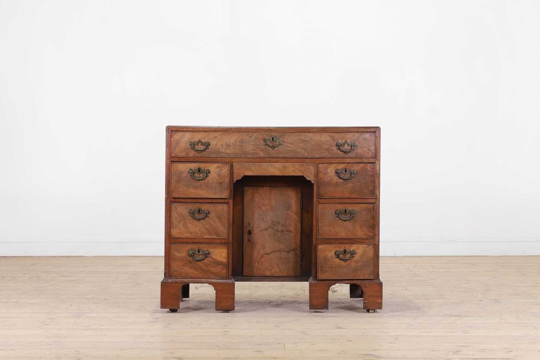 A George III mahogany caddy-top kneehole desk, second half of the 18th century,: A George III mahogany caddy-top kneehole desk, second half of the 18th century, the rectangular top above an arrangement of drawers surrounding a cupboard, raised on bracket feet and castors 94cm wide