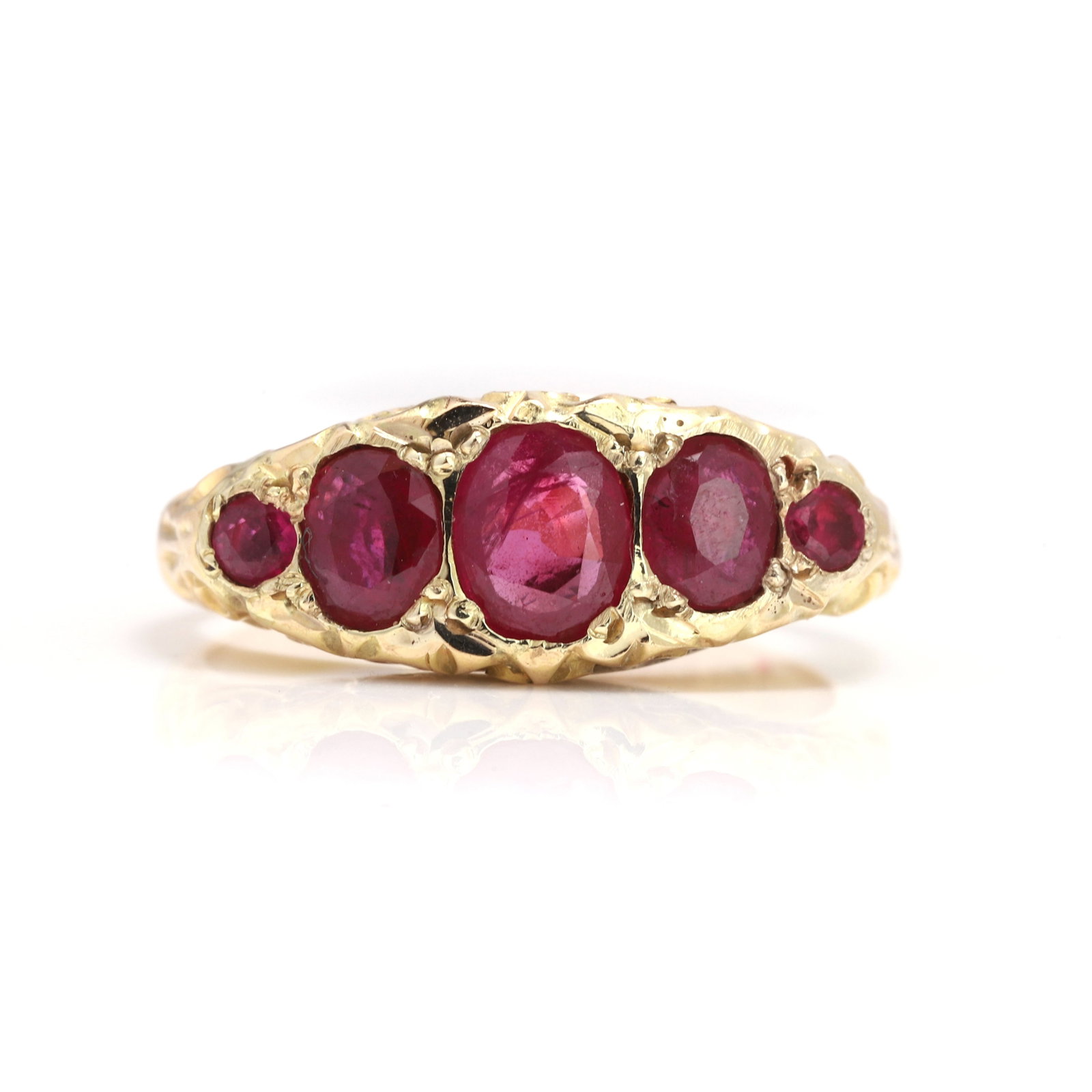 A late Victorian18ct gold ruby five stone ring,: A late Victorian18ct gold ruby five stone ring, set with three graduating oval mixed cut rubies flanked by two circular cut rubies, to an engraved scroll gallery, hallmarked 18, Chester, date stamp