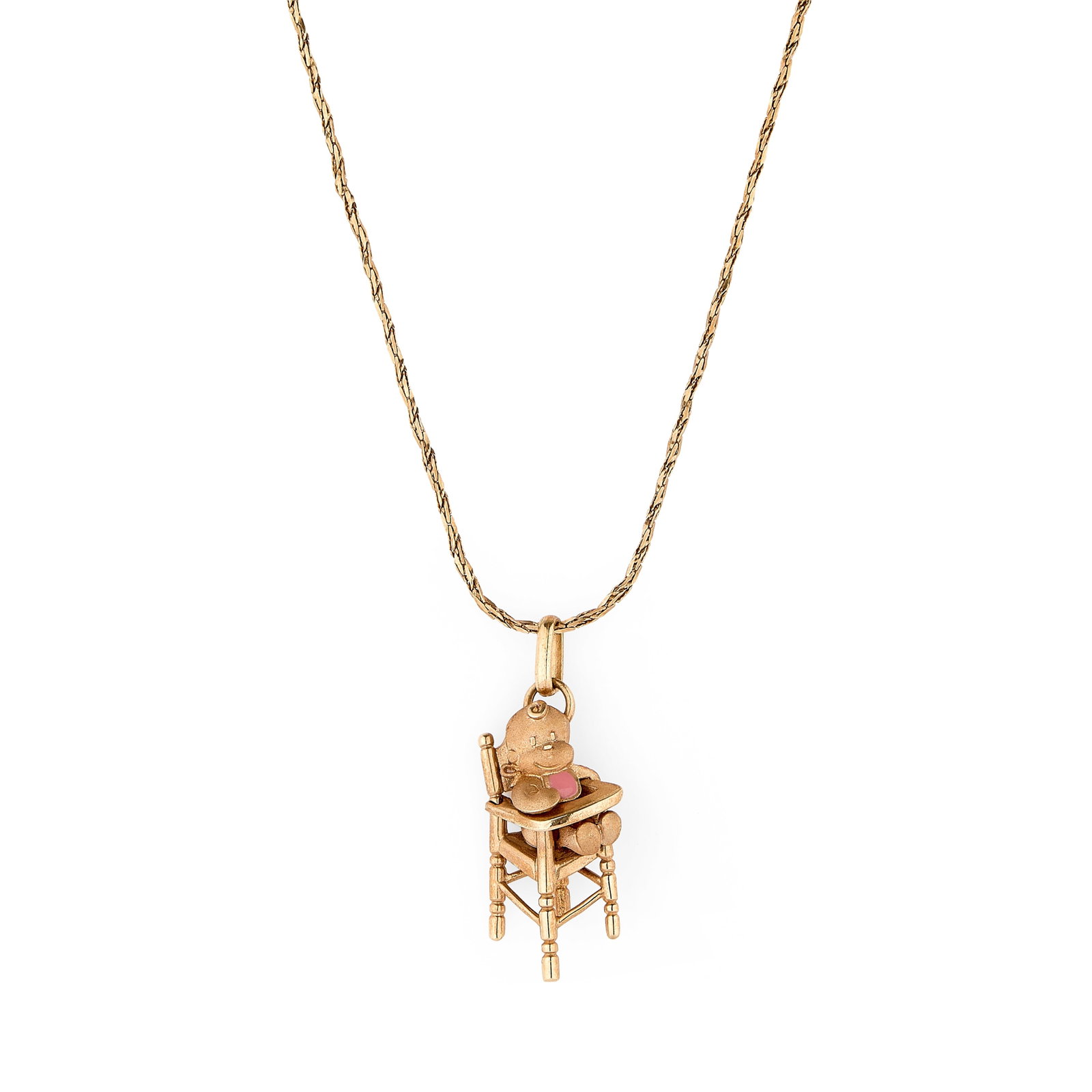A baby in high chair pendant and chain,: A baby in high chair pendant and chain, depicted with a pink lacquer bib to an articulated parallel bail with engraving to reverse 'dah mucho pedir poco', stamped 750, tested as 18ct gold, suspended