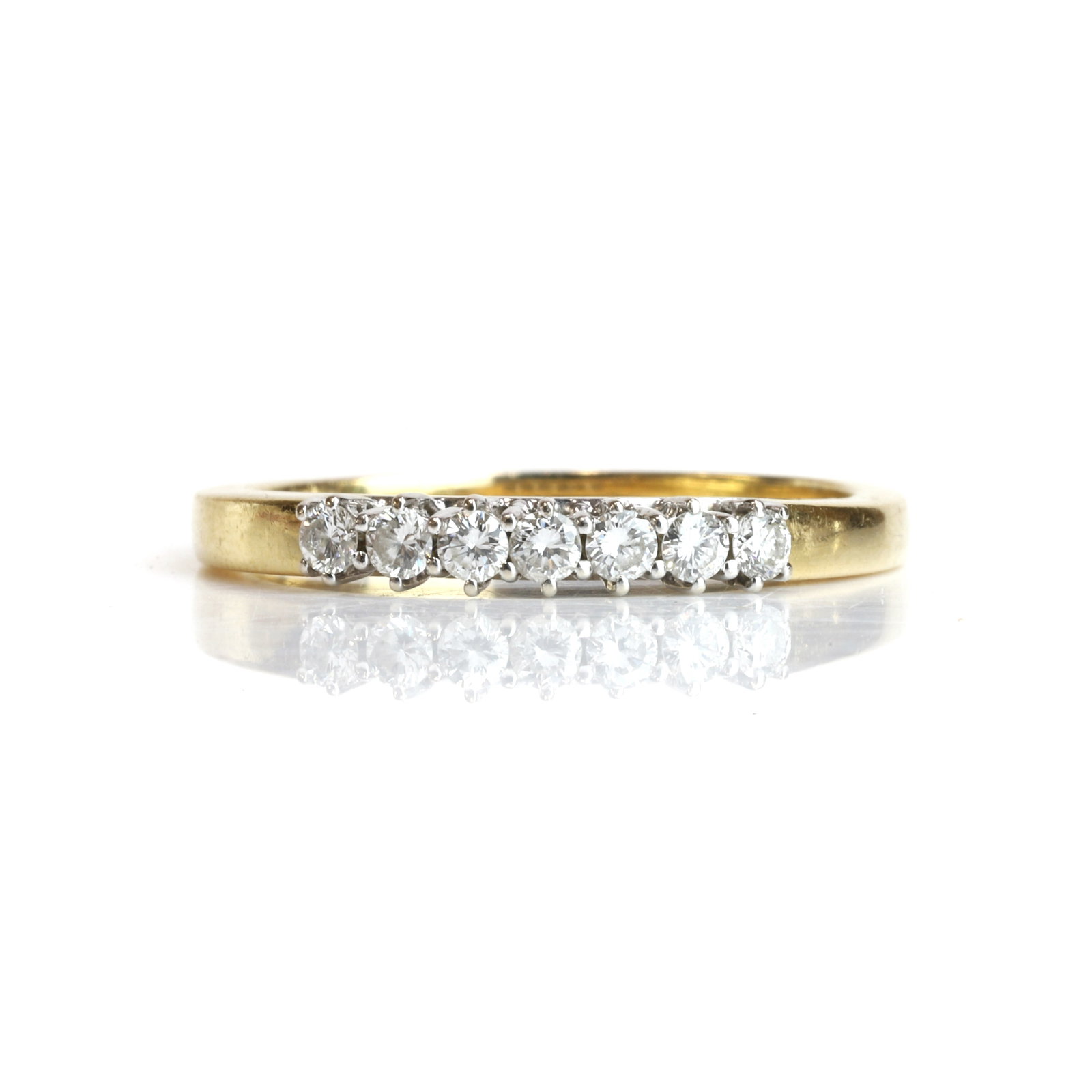 A diamond half eternity ring,: A diamond half eternity ring, claw set with seven round brilliant cut diamonds, mounted in unmarked yellow metal, stamped 18K 750, total diamond weight approximately 0.70ct (Ring size J; 4.6g)