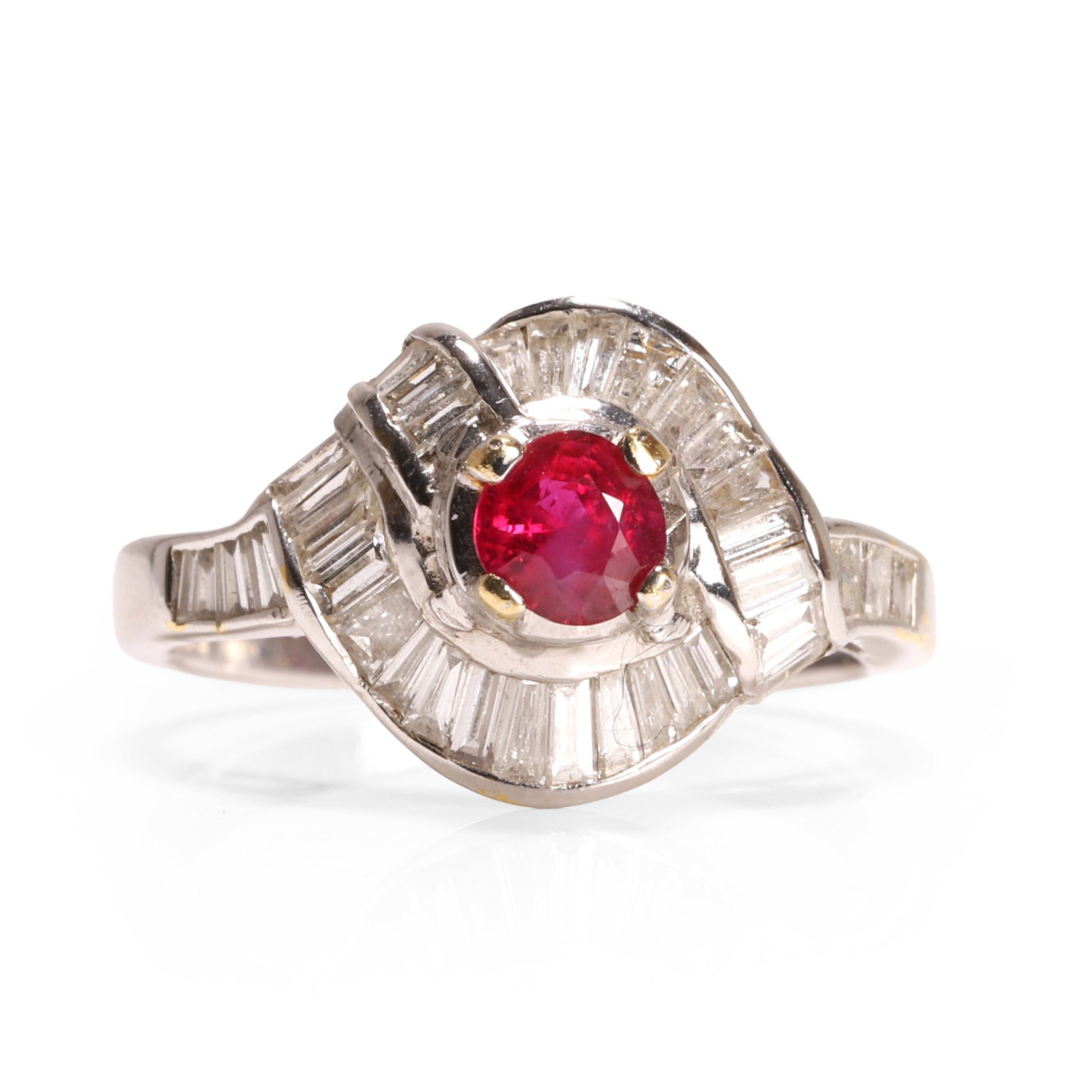 A ruby and diamond crossover design ring,: A ruby and diamond crossover design ring, set with a circular cut ruby, to a wraparound surround of baguette cut diamonds, in rhodium plated yellow gold, surface tested as approximately 18ct (Ring