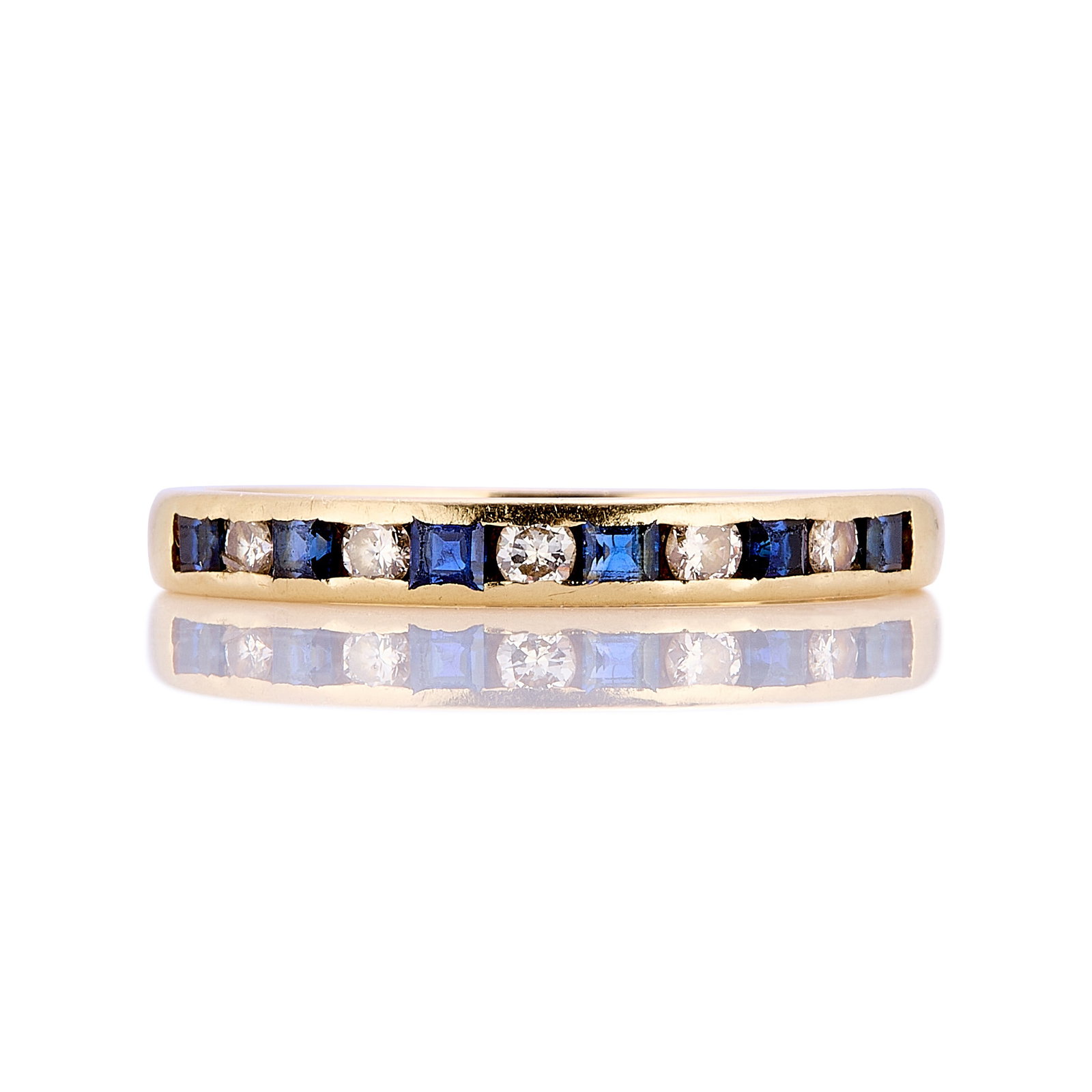 An 18ct gold sapphire and diamond half eternity ring,: An 18ct gold sapphire and diamond half eternity ring, channel set with square cut sapphires and round brilliant cut diamonds, one diamond fractured, hallmarked London 1978 (Ring size T; 2.6g) Footnote