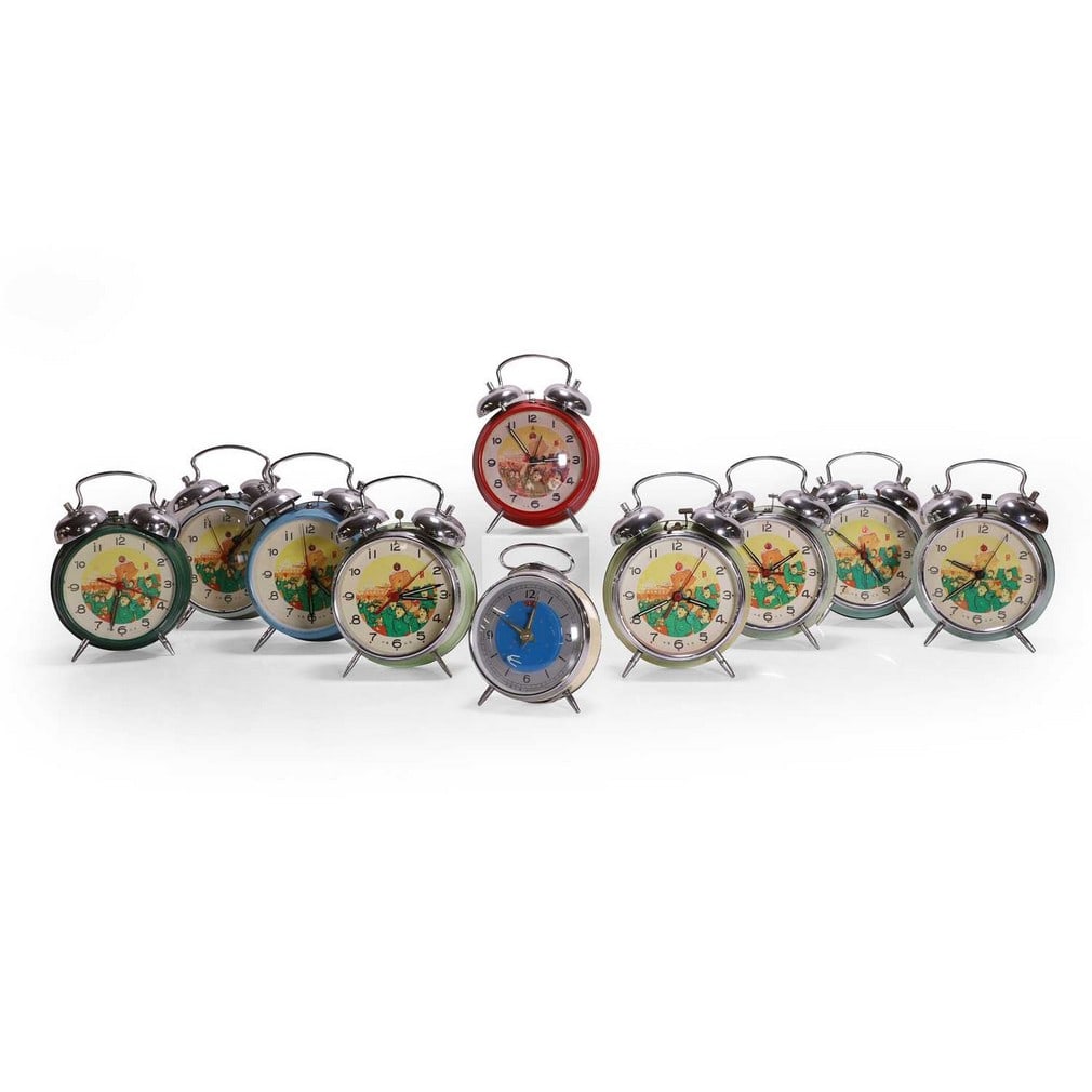 A group of ten Chinese Cultural Revolution alarm clocks, circa 1970,: A group of ten Chinese Cultural Revolution alarm clocks, circa 1970, nine depicting figures holding red books, the tenth depicting a comet (largest 13cm wide, 6cm deep, 18cm high) (10) Footnote: 'I bo