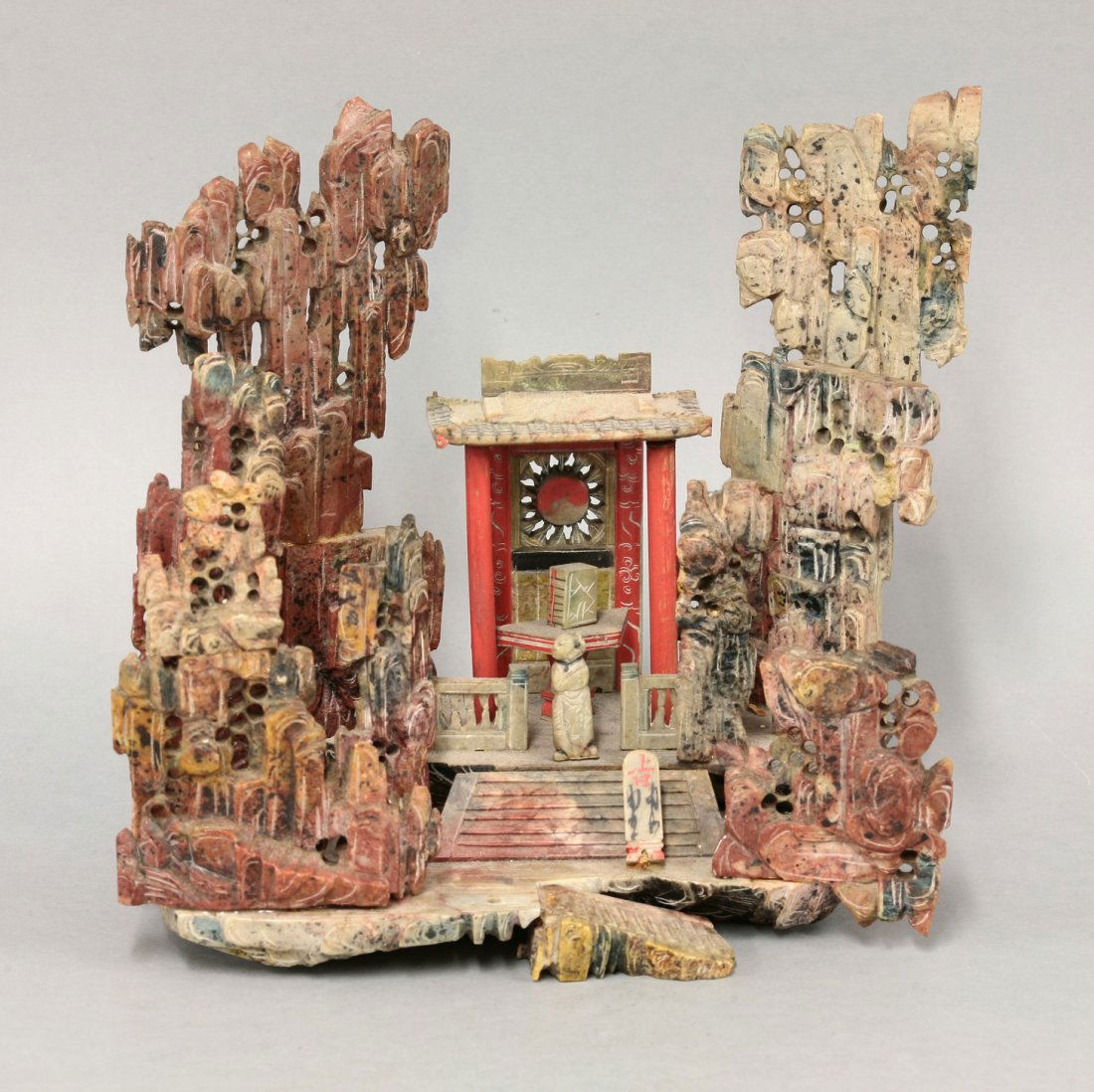 A Chinese soapstone diorama, of a shrine amongst: A Chinese soapstone diorama, of a shrine amongst towering rocks, 22.5cm