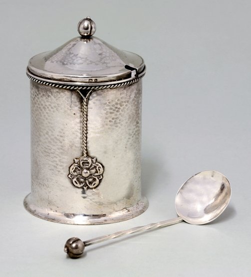 A silver preserve pot and spoon, designed by AE Jones: A silver preserve pot and spoon, designed by AE Jones and retailed by George Lawrence Connell, Birmingham 1909, of spot hammered cylindrical form, with ropework border and tassels terminating in tudor