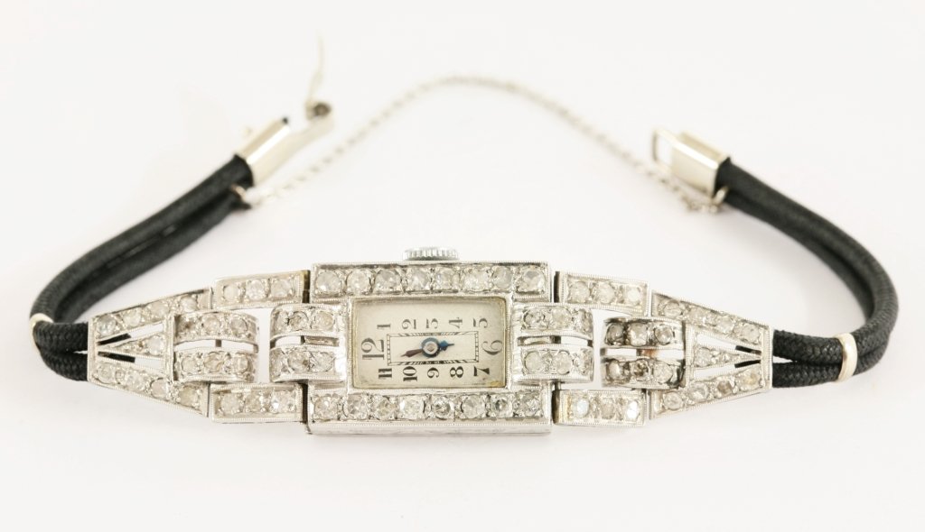 A ladies Art Deco diamond set cocktail watch, a: A ladies Art Deco diamond set cocktail watch, a rectangular silvered dial, with Arabic numerals and blued steel hands. A line of eight cut diamonds, grain set to the bezel, with pairs of arched lugs t