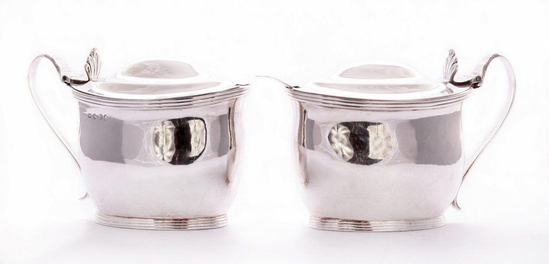 A pair of George III silver mustard pots, by John: A pair of George III silver mustard pots, by John Edwards, London 1800, of baluster form on oval bases with reeded borders, the reeded scroll handles with shell thumbpieces, and an old english pattern