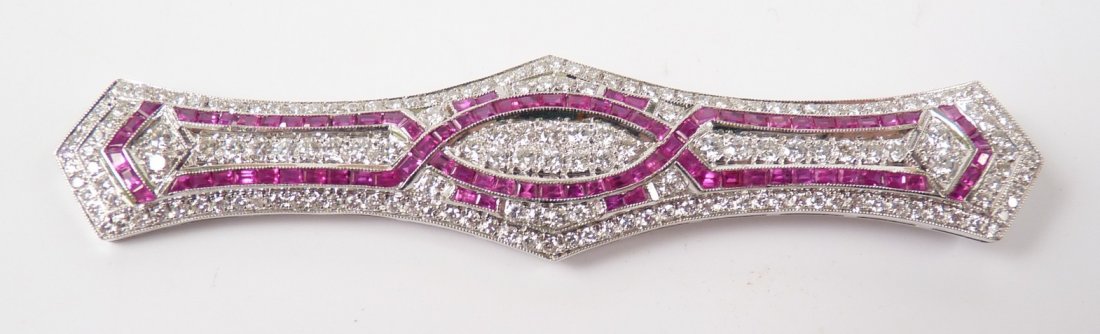 An Art Deco style ruby and diamond bar brooch, the: An Art Deco style ruby and diamond bar brooch, the serpentine edged bar, 80mm in length, with two overlapping rows of milligrain set calibré rubies, to a brilliant cut diamond pavé set ground, with 