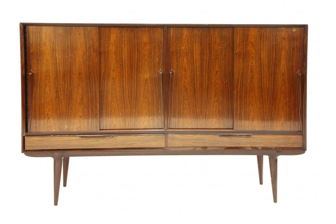 A Danish rosewood high sideboard, model no. 13,: A Danish rosewood high sideboard, model no. 13, designed by Gunni Omann in 1961, manufactured by Omann Jun, with sliding doors enclosing shelves over two drawers, on a turned wood stand, 180cm wide 45