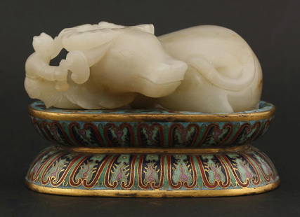 An unusual jade Buffalo and conforming cloisonné Stand,: An unusual jade Buffalo and conforming cloisonné Stand, both late 19th century, the former in a good white stone, a boy with ruyi standing by its head, its rump with a river of brown,9.6cm,the waiste