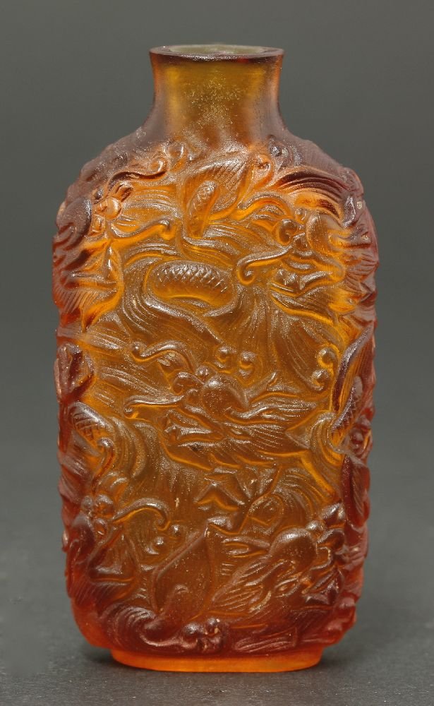 A fine and rare Imperial Snuff Bottle, mark and period: A fine and rare Imperial Snuff Bottle, mark and period of Qianlong, the amber glass oval section body well carved with five clawed dragons, amongst clouds, faint engraved Qianlong nian zhi,7cm