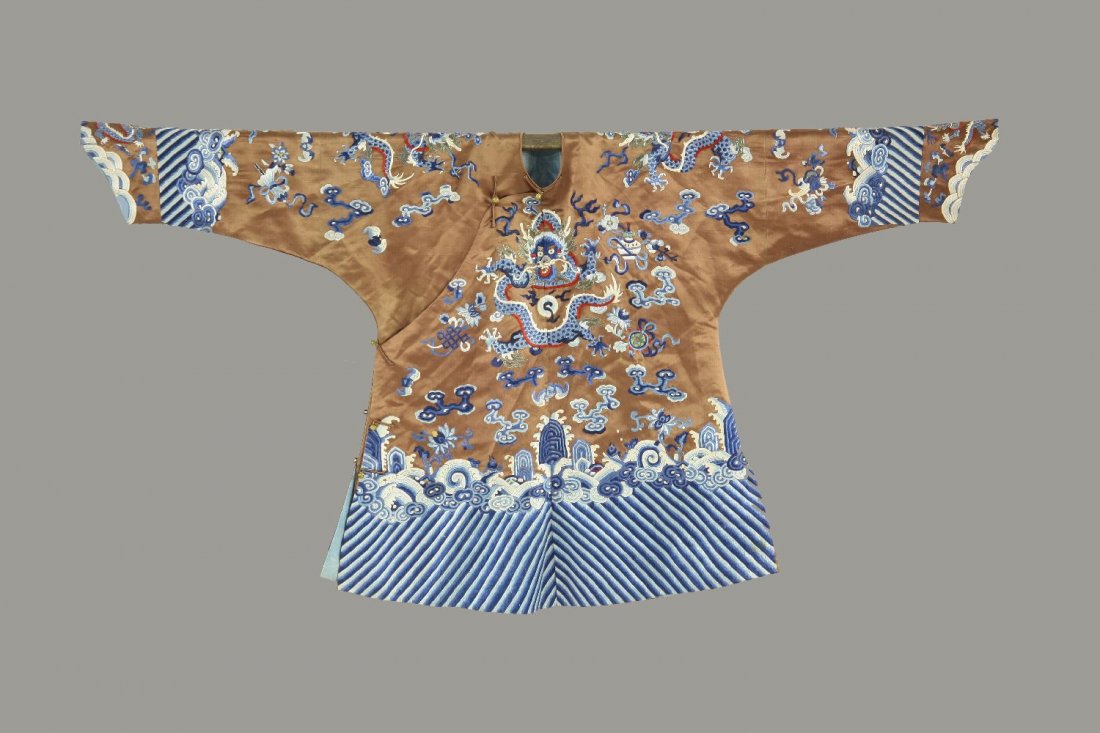 A dragon jacket, Qing dynasty, the dragons in colours: A dragon jacket, Qing dynasty, the dragons in colours with five claws, all chasing the flaming pearls amongst Buddhist emblems, all above crested waves, fish and rocks on brown silk groundFormerly bel