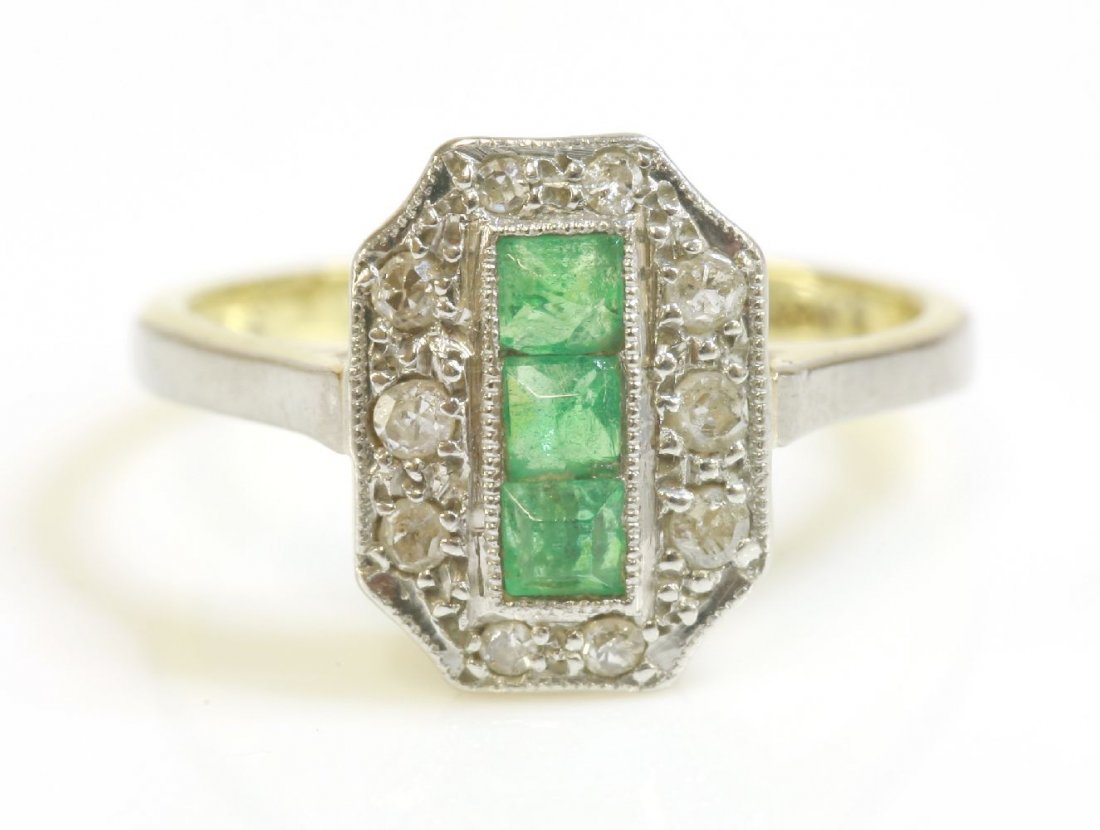 An Art Deco emerald and diamond rectangular cluster: An Art Deco emerald and diamond rectangular cluster ring with cut corners, c.1925, three square calibré cut emeralds set in a vertical line through the centre of the head, surrounded by ten, eight cu