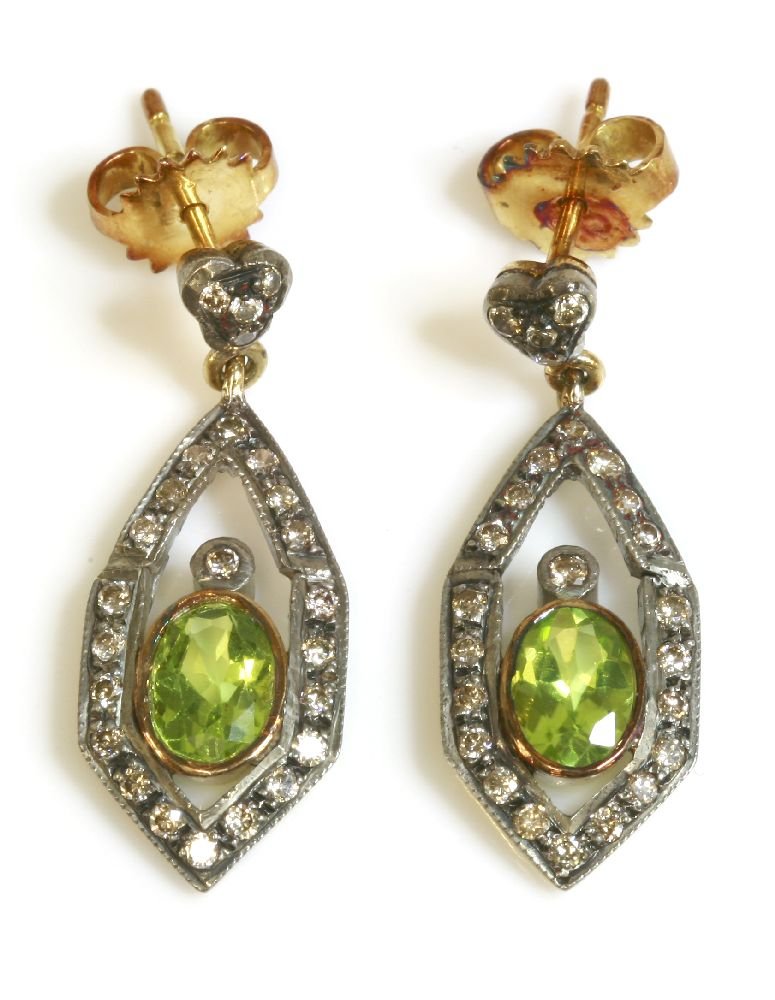 A pair of Continental Art Deco style peridot and: A pair of Continental Art Deco style peridot and diamond drop earrings, an oval mixed cut peridot, rub set in a gold collet, with a brilliant cut diamond above, to an outer elongated hexagonal frame o