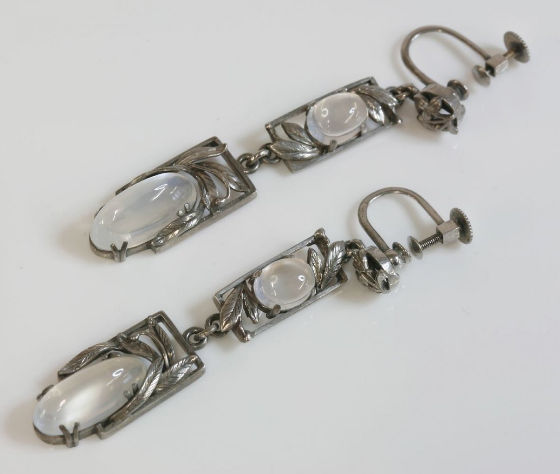 A pair of silver Arts and Crafts moonstone drop: A pair of silver Arts and Crafts moonstone drop earrings, c.1930, attributed to Bernard Instone, each earring composed of graduated rectangular frames, inset with oval cabochon moonstones, surrounded