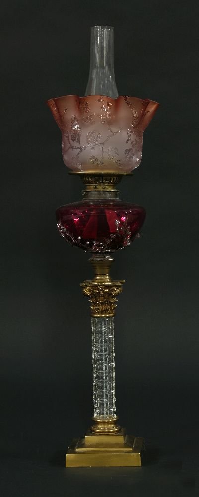 A Victorian brass Corinthian column oil lamp, with: A Victorian brass Corinthian column oil lamp, with stepped base and cut glass column, the cranberry glass reservoir with applied clear glass leaves, inscribed 'Wright & Butler, Birm.' on one adjuster,