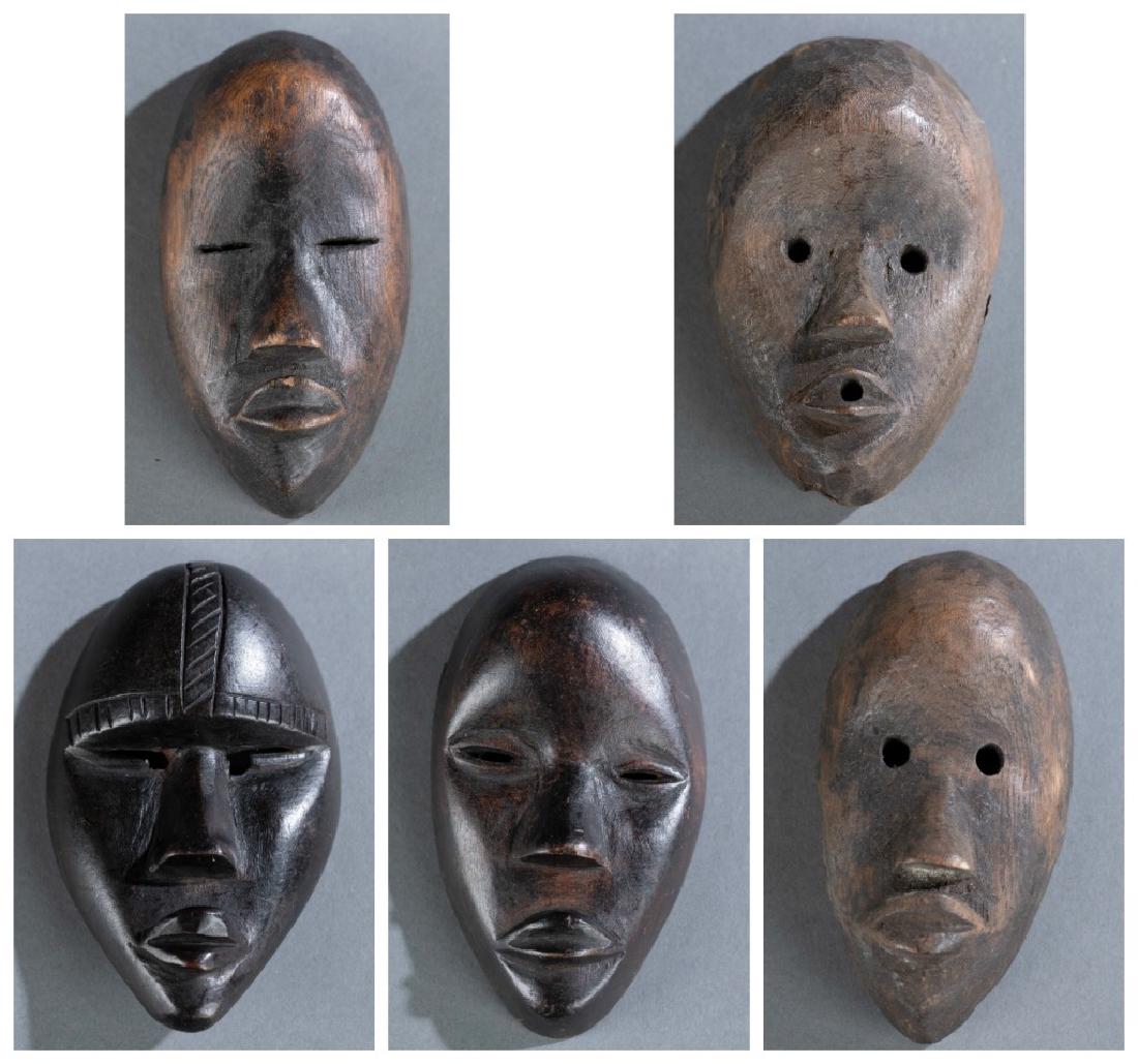 5 Dan masks. 20th century.: A group of five Dan passport masks. 20th century. ++Three oval shaped masks with protruding nose and lips with open slit eyes. ++Two oval shaped masks with protruding nose and lips with circular holes