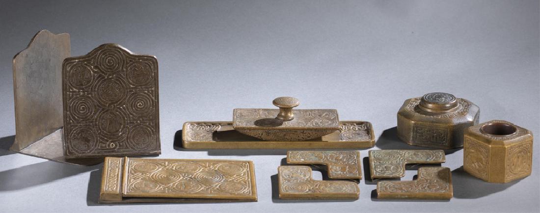 8 piece Tiffany Zodiac Bronze Desk Set.: An eight-piece Tiffany Studios Gilt Bronze Desk Set. circa 1900. Marked "Tiffany Studios New York." Includes bookends, notepad holder, blotter, ink well, pen brush wipe, blotter corners, and pen tray.