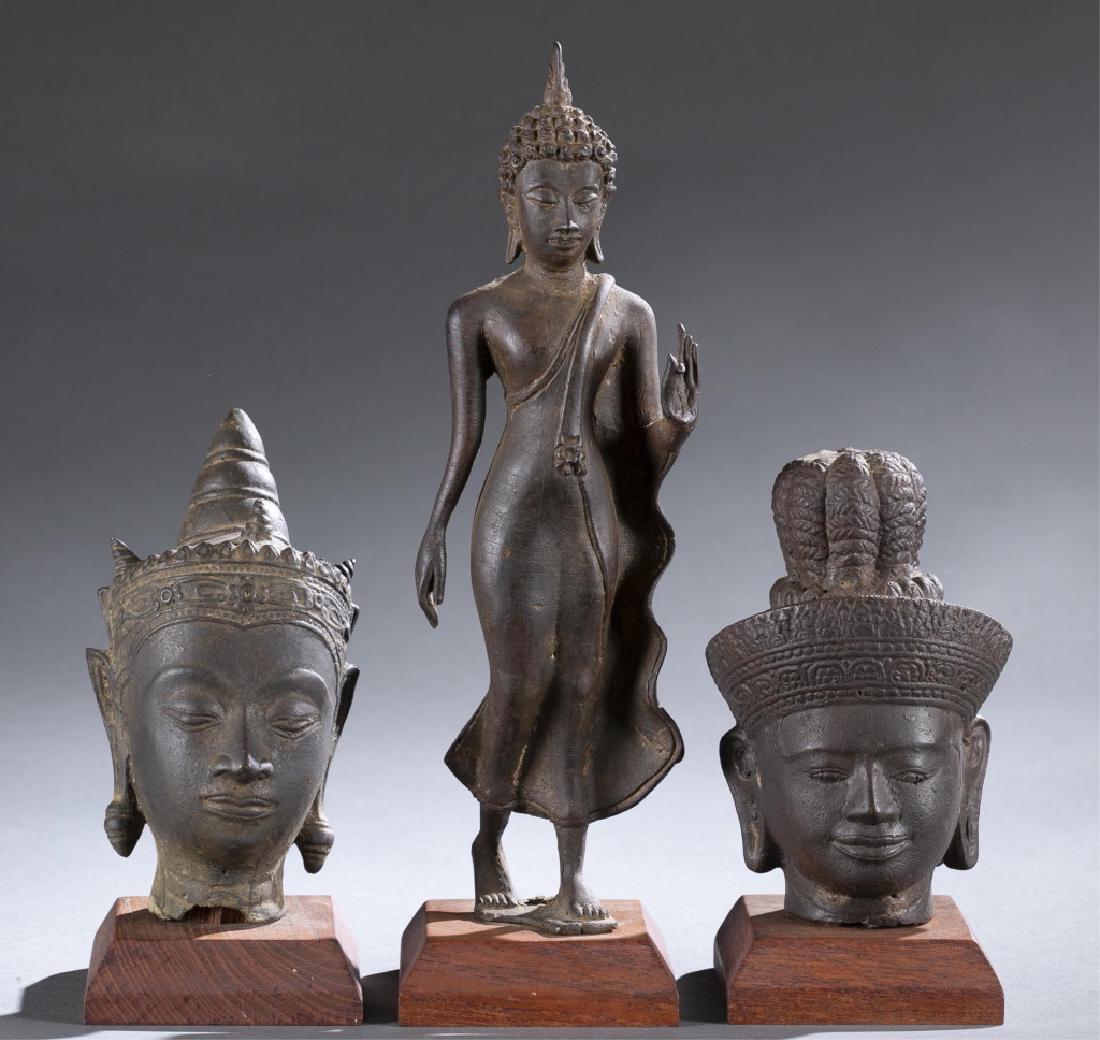 3 bronze Southeast Buddha statues.: A group of three bronze Southeast Buddha statues. ++ Standing Thai Buddha on wooden stand. In the gesture of fear dispelling/ Abhaya Mudra. 11 1/4"; 12 1/4" (w/stand) ++ Two Cambodian bronze Buddha he