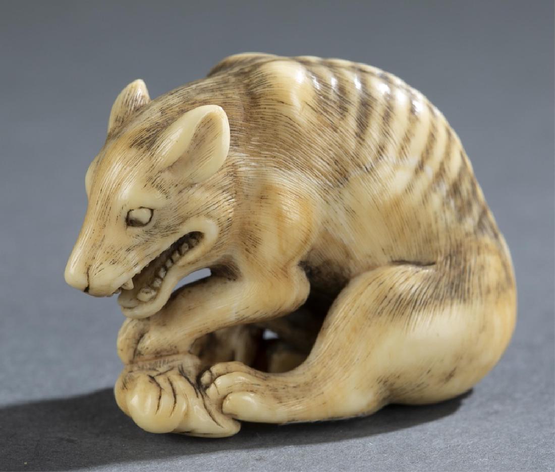 Netsuke of a wolf, ca. 1800, Okakoto.: A netsuke of a wolf eating a deer leg. Japan. Circa 1800. Signed - Okakoto. H: 1 3/8" (3.5cm); W: 1 3/4" (4.5cm). 97._x000D_ Provenance: The Harry Glass Collection, Long Island, NY.