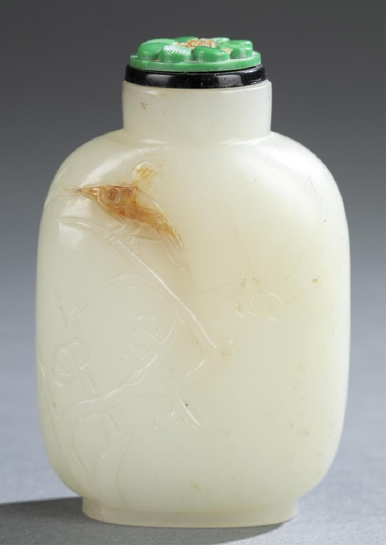 Jade snuff bottle.: A Chinese jade snuff bottle. Celadon white jade with yellow inclusion. Carved with magpie over plum flower branch design on front. Flattened rounded rectangular form, on oval foot. 2 3/4hâ€.