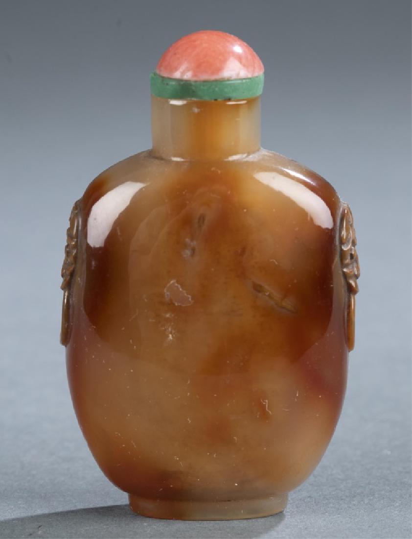 Agate snuff bottle.: A Chinese agate snuff bottle. 19th century. Russet, tan and brown agate. Flattened rounded rectangular form, with mask ring handles to both shoulders, on oval foot, with red and green glass stopper. W