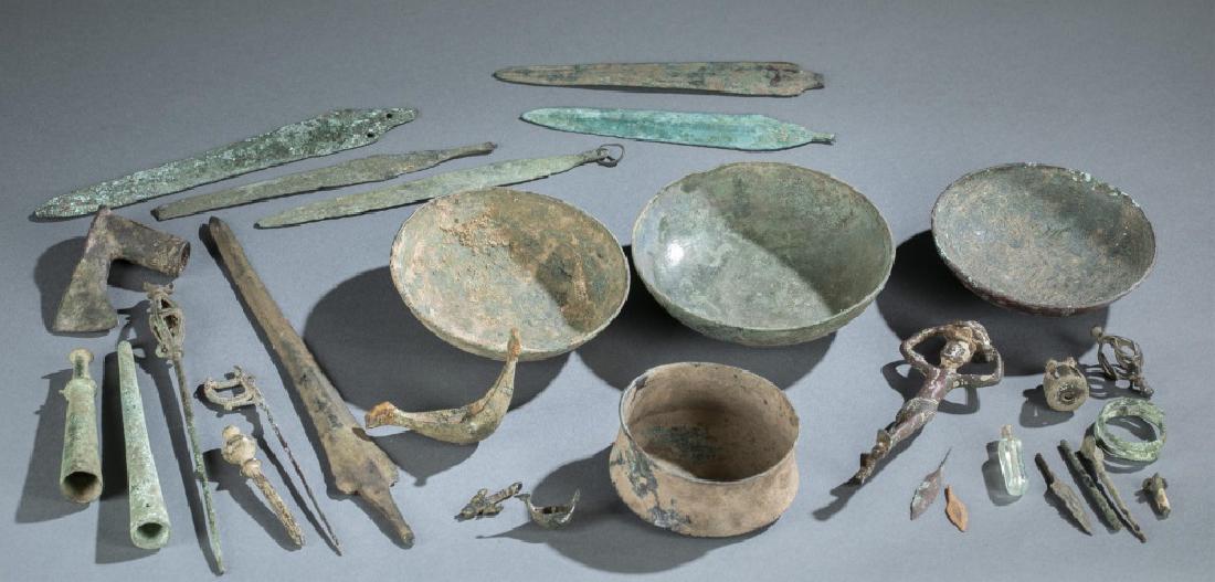 30 Ancient bronze and glass artifacts.: A group of thirty ancient bronze and glass artifacts including weapons tips/ blades, bowls, decorative objects, bells, and tools. Largest: 11 3/4" x 1 3/4" x 1/8". Smallest: 1" x 1".