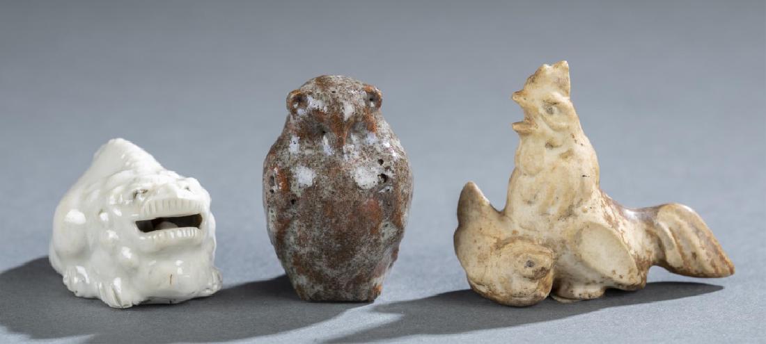 3 Animal Netsuke, 19th c.: A group of three netsuke. Japan. 19th century. ++ Porcelain of a Shishi with movable ball in mouth. Hirado ware. H: 15/16 in (2.4 cm). ++ Ceramic of an owl glazed in a brownish color. H: 1 1/2 in (3.8