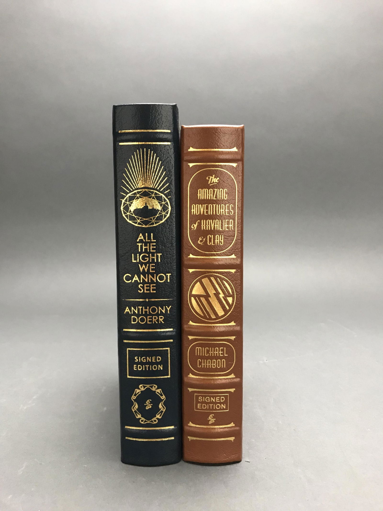 2 vols. Easton. Signed Eds. WWII Fiction.: [Easton Press] 2 volumes of Easton Press, both signed by the authors. Both leather bound with gilt ornamentation, all edges gilt. (1) Chabon, Michael. The Amazing Adventures of Kavalier & Clay. 2013.