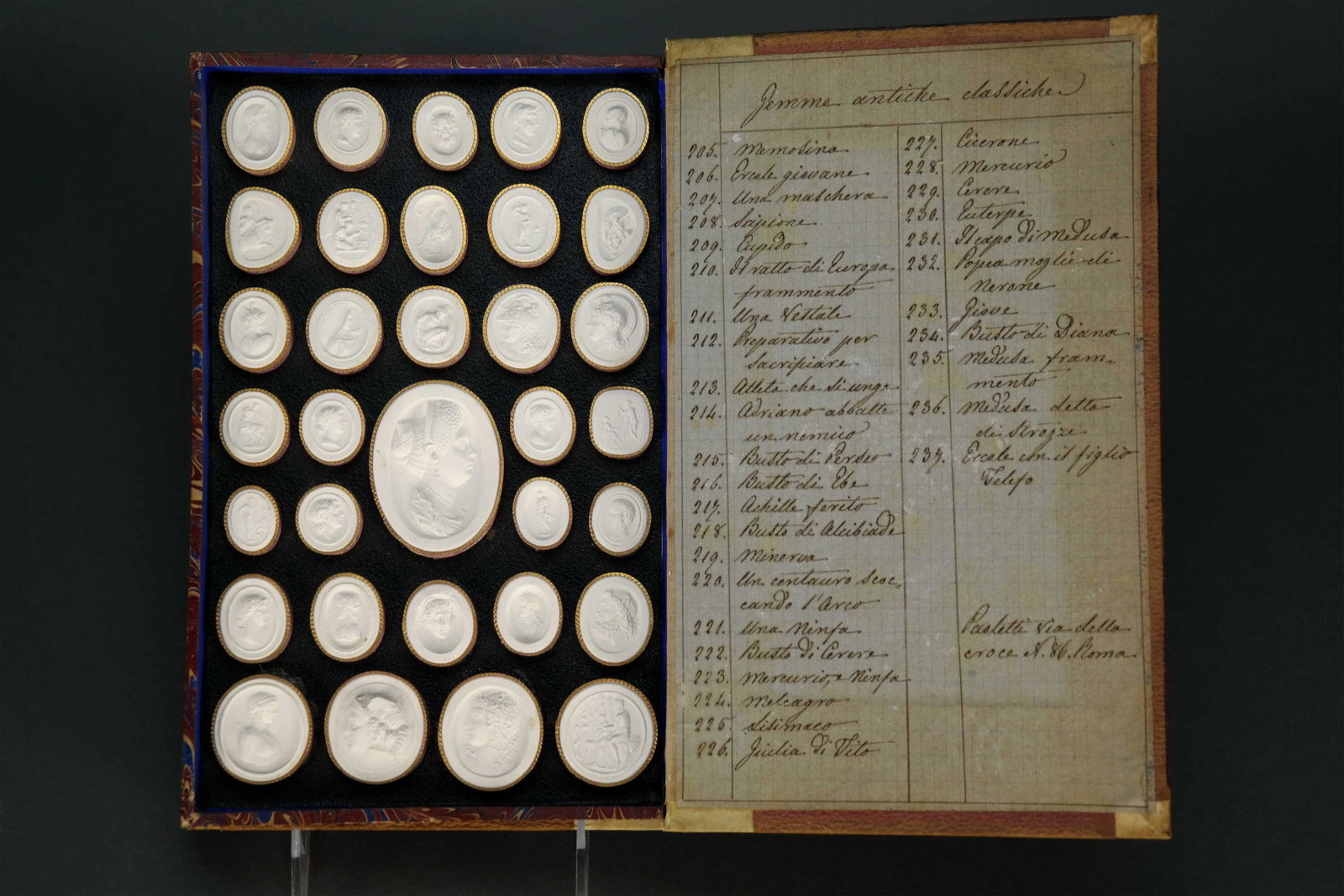 Paoletti Impronte. 68 cameos. Double sided. 1800s.: [Grand Tour] Paoletti Impronte. 68 plaster cameo pieces in a double sided book box. List corresponding to each piece are on the inside of each flap. Paoletti via della croce, 86, Roma written at the b