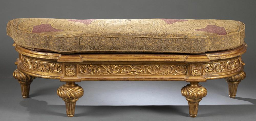 Christopher Guy, giltwood bench.: Christopher Guy giltwood bench. 20th century. Parquetry top, beneath cushion. Giltwood with decorative scroll, gadrooning, and floral carving. Four decorative gadrooned and reeded carved feet. Wear to