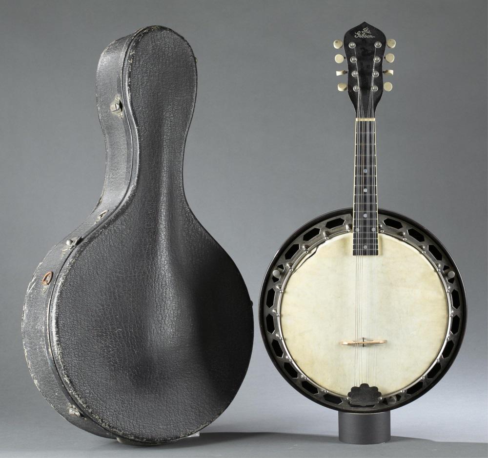 "The Gibson", Mandolin Banjo.: A "The Gibson" Mandolin Banjo. Serial number 9773-8. Eight-strings. Resonator removable. Marked on top of head. Case included. Tear on left drum head. 25" x 13" x 3 1/2". Case: 26 1/2" x 14 1/2" x 5".