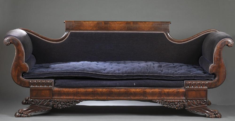 American Empire, mahogany sofa, early 19th c.: An American Empire mahogany sofa in the style of Duncan Phyfe. Circa early 19th century. Flame mahogany veneer, scrolled crest rail. Navy upholstery and tufted cushion. Flanked by scrolled arms on ela