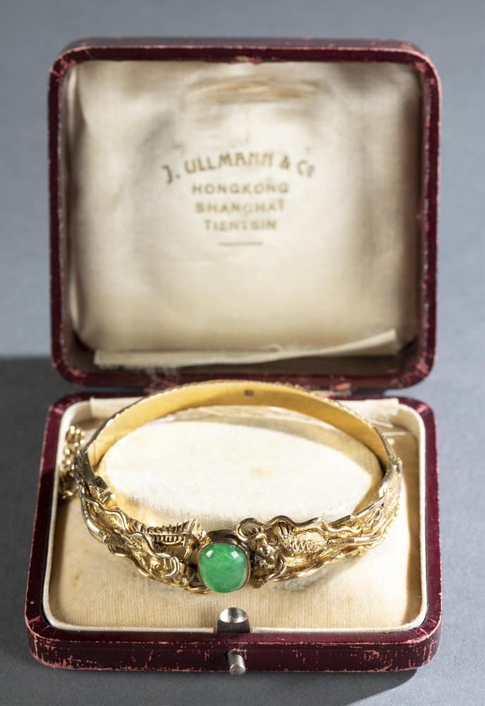 Chinese Mandarin hinged bangle bracelet.: A Chinese Mandarin gold hinged bangle bracelet. Circa 1905-1915. 18-22kt yellow gold. Hand wrought mirror image of imperial dragons holding an oval cushion shaped strong bright apple greed jadeite sto