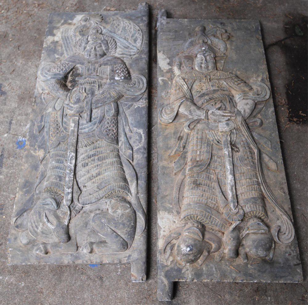 2 Chinese carved stone tomb doors.: A pair of Chinese Han dynasty style stone tomb doors. 51 1/2" x 19 3/4" x 1 3/4". ++ Relief carving depicting a Buddhist guardian figure standing on a bull. ++ Relief carving depicting a Buddhist guar