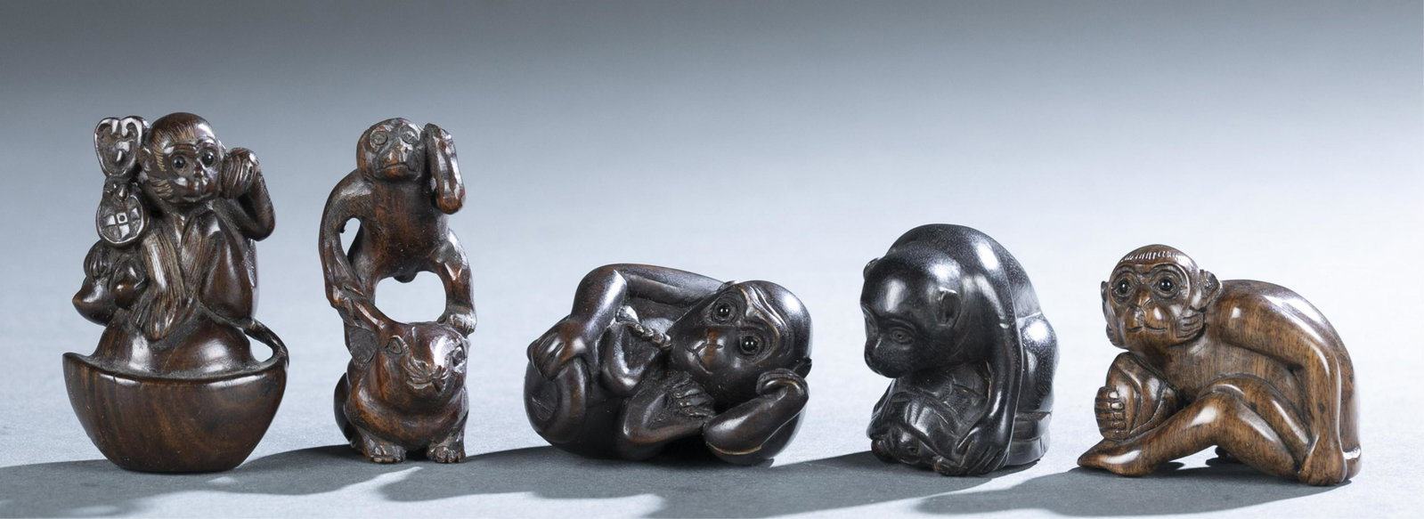 5 wooden Netsukes of Monkeys.: A group of five hardwood netsuke of monkeys. 20th century. Depicting monkeys in various positions: holding peach, climbing over sycee, riding a rabbit, sitting on a turtle, and reclining. Largest: 2 1